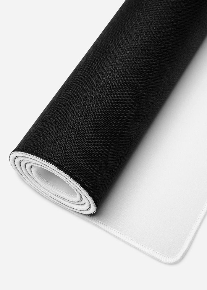 Black and white desk mat partially rolled showing layers and stitching
